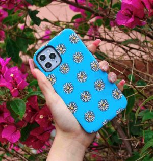 Hand holding a blue phone case decorated with white and yellow daisies