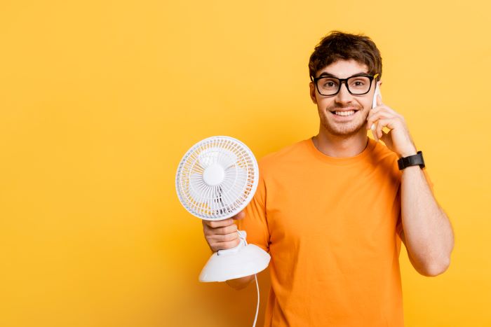 Man cooling overheated phone with fan