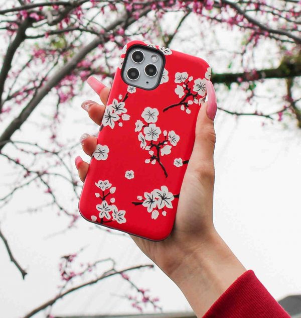 Hand holding a red phone case decorated with white blossom